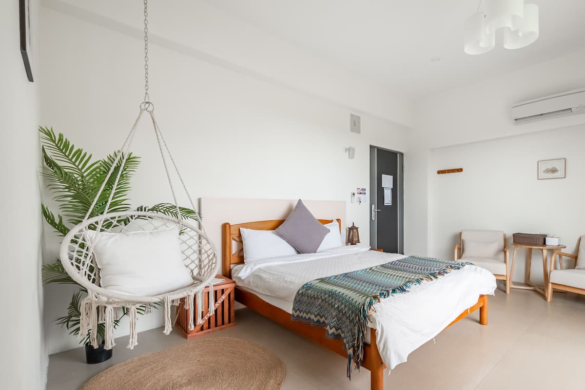 Ein modernes Schlafzimmer mit einem Bett, einem Hängesessel, einem Holzstuhl und einem kleinen Tisch.