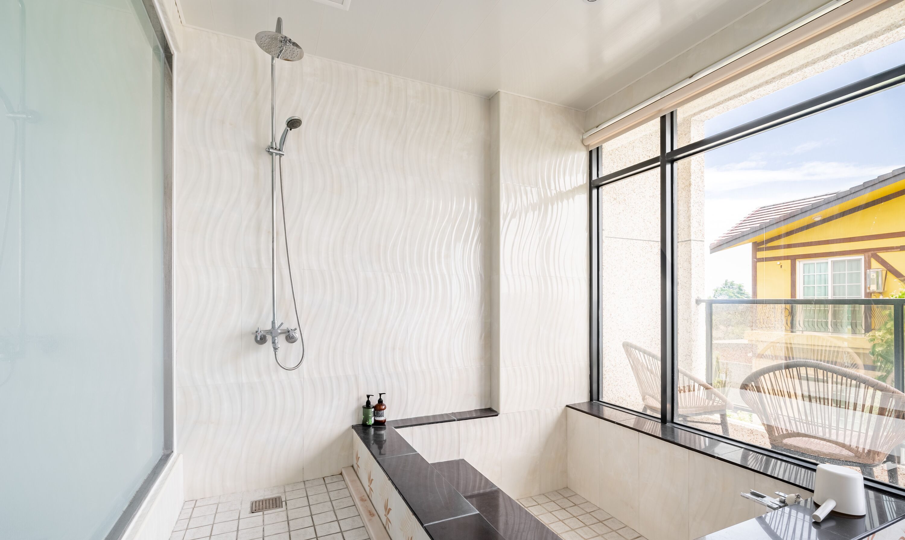 Une salle de bain moderne équipée d’une douche, d’une baignoire et d’une fenêtre donnant sur l’extérieur.