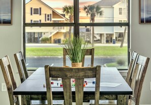 Une table à manger avec des chaises, une plante en pot et une fenêtre donnant sur des maisons.