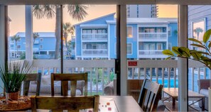 A balcony with wicker furniture, a view of blue buildings, and a pool.