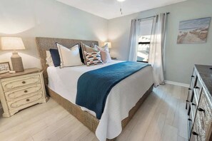 A neatly arranged bedroom with a bed, bedside tables, and a dresser.