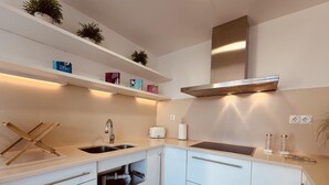 Una cocina moderna con gabinetes blancos, una campana extractora de acero inoxidable y un lavavajillas integrado.