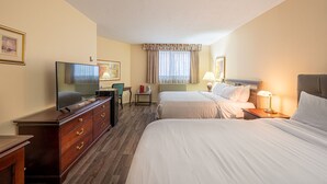 Une chambre d’hôtel avec deux lits, une télévision, un bureau et une chaise.