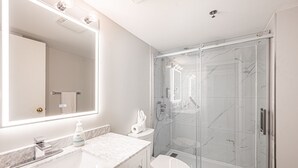 A modern bathroom with a glass-enclosed shower, a marble sink, and a large mirror with built-in lighting. - Chambre 2 Lits/Room 2 beds (Saint-sauveur)