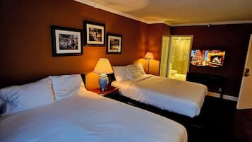 A hotel room with two beds, a television, and framed pictures on the wall.