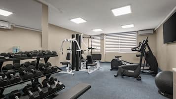 A gym with various exercise equipment, including dumbbells, a bench, and cardio machines.