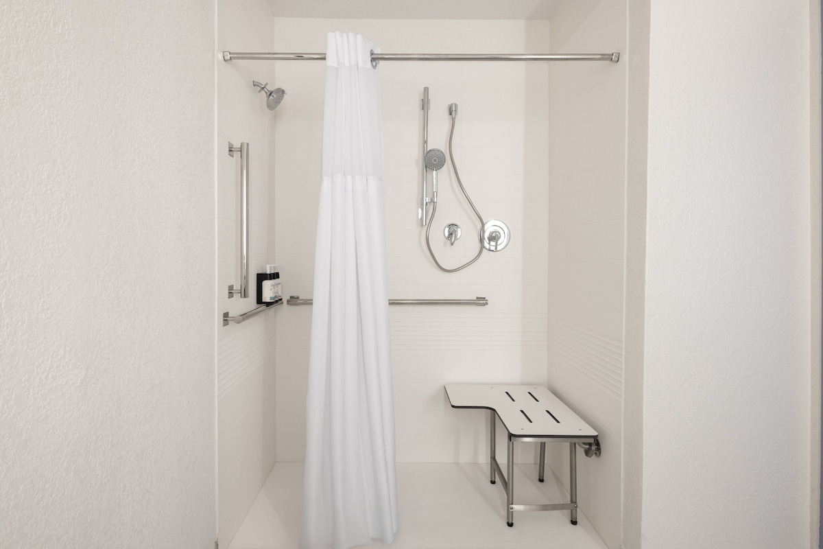 Une salle de bain moderne équipée d’une douche, de toilettes et d’un petit banc.