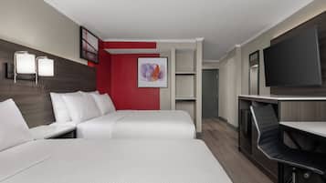 Habitación de hotel con cama, escritorio, silla, televisión y un cuadro en la pared.