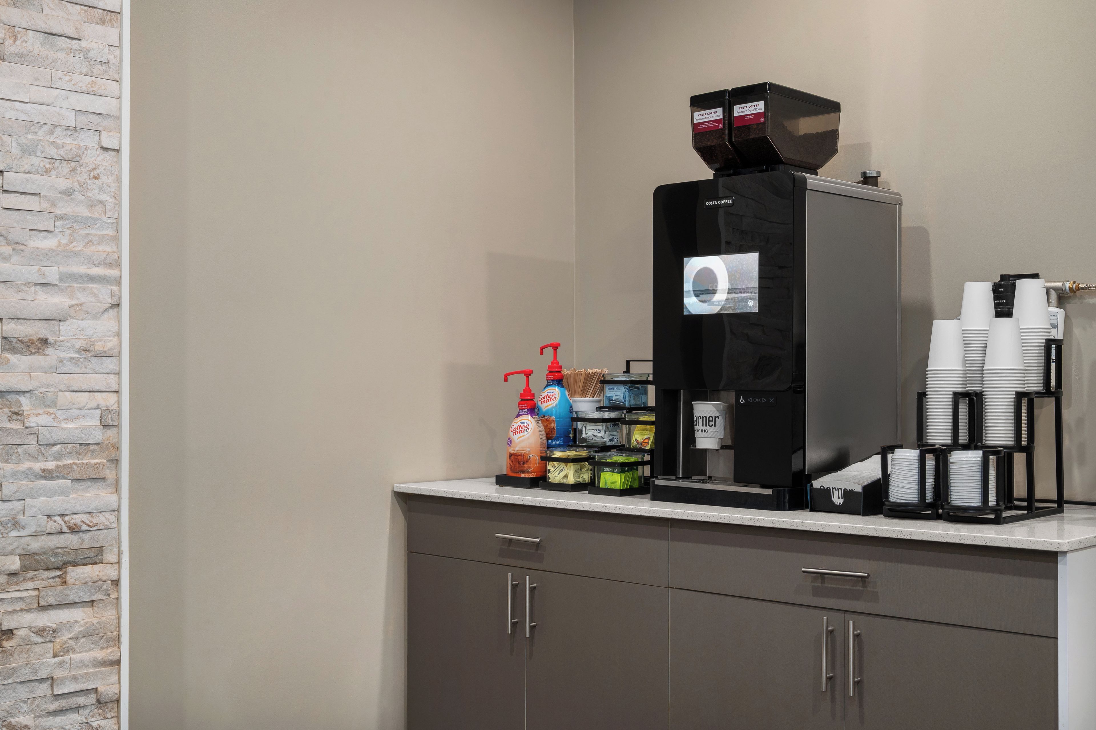 A coffee station with a coffee machine, disposable cups, and coffee-related products.