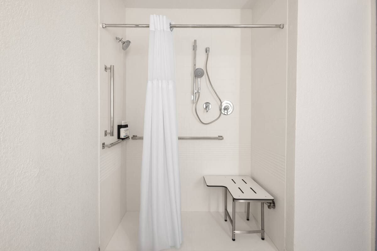 Ein modernes Badezimmer mit Dusche, Toilette und einer kleinen Sitzbank.