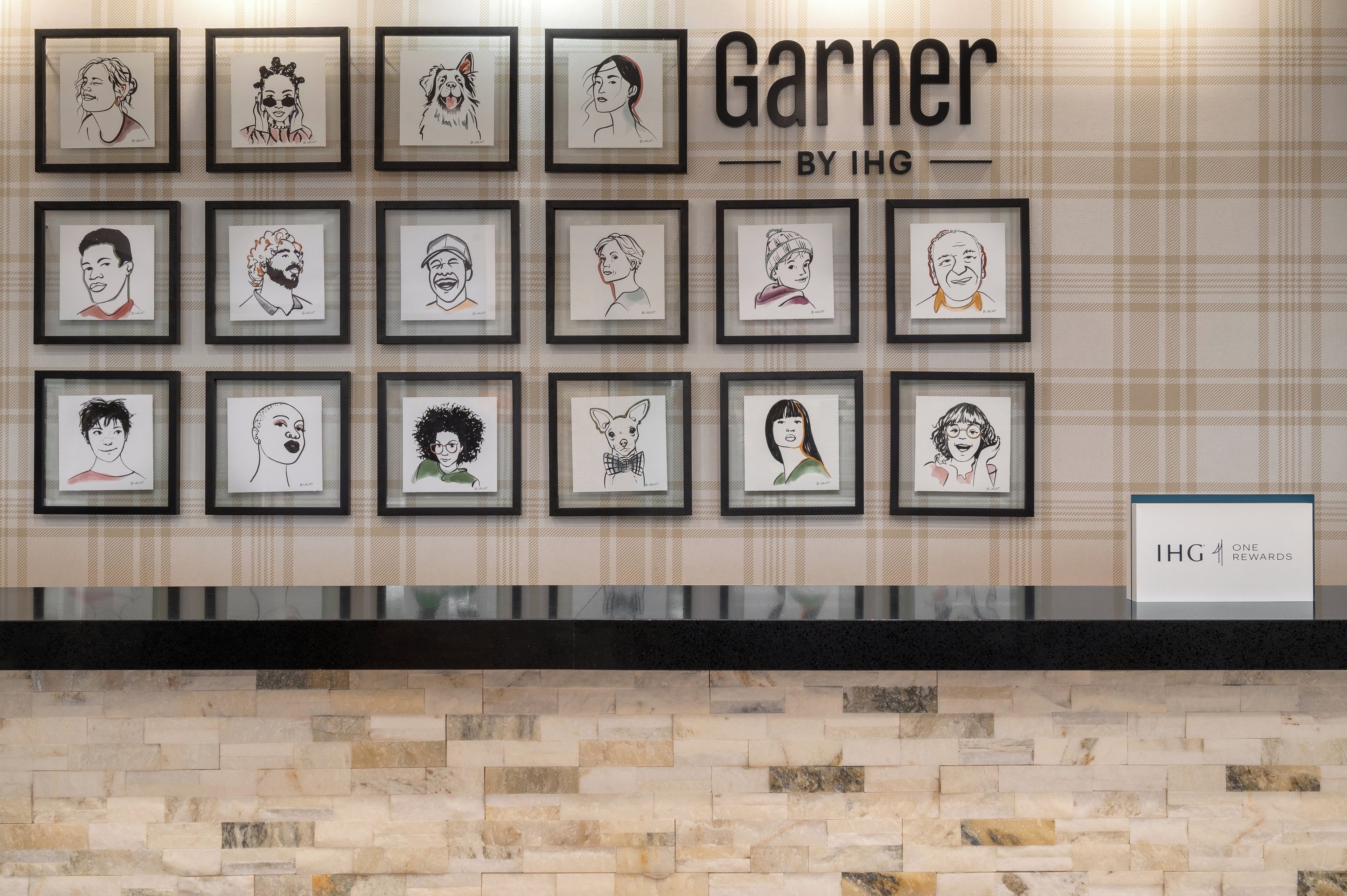 Un mur décoratif composé de plusieurs cadres contenant des portraits en noir et blanc, avec l’inscription « Garnier by IHG ».