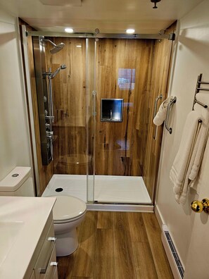 Een moderne badkamer met een douchecabine van glas, een toilet en een wastafel.