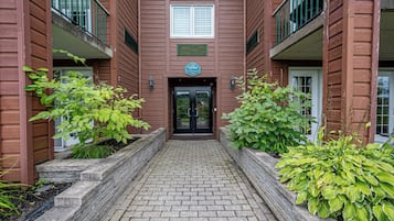 A brick building with a central entrance, two balconies, and a sign above the door.