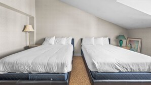 Une chambre d’hôtel avec deux lits, une lampe, un tableau et un sol recouvert de moquette.