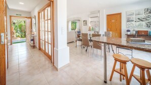 A modern kitchen with a marble countertop, wooden stools, and a dining area with chairs. - Sunwing Beach by Interhome (Port d'Alcúdia)