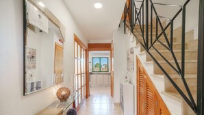 A hallway with a wooden bench, a mirror, and a staircase with black railings. - Sunwing Beach by Interhome (Port d'Alcúdia)