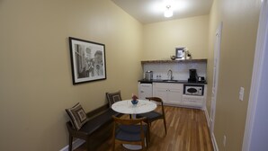 A compact kitchen with a dining table, chairs, a bench, and a framed picture on the wall. - Greyhound Inn - Classic Double Suite (Tyler)
