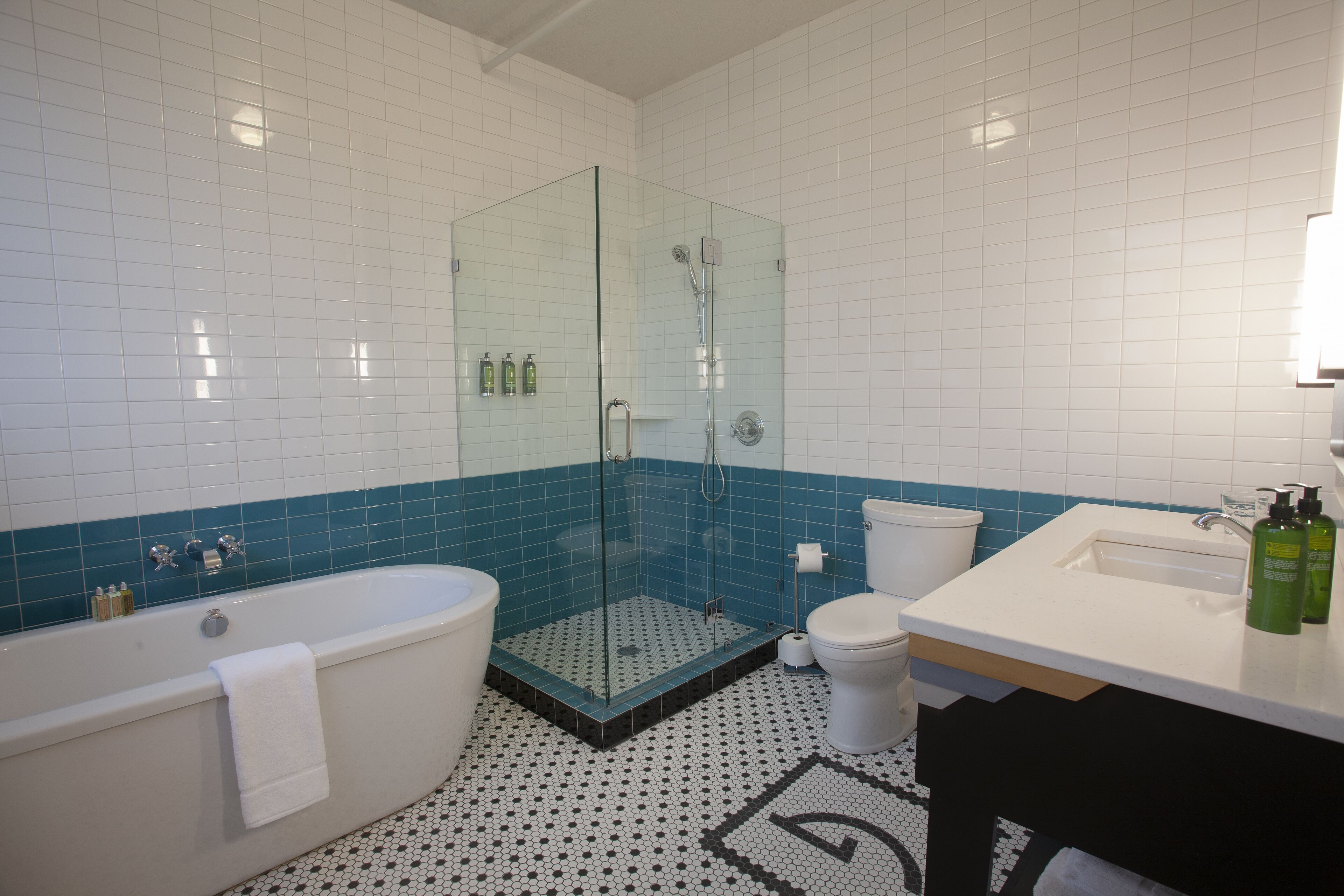 Un baño con ducha de vidrio, bañera, inodoro y lavamanos con artículos de aseo.