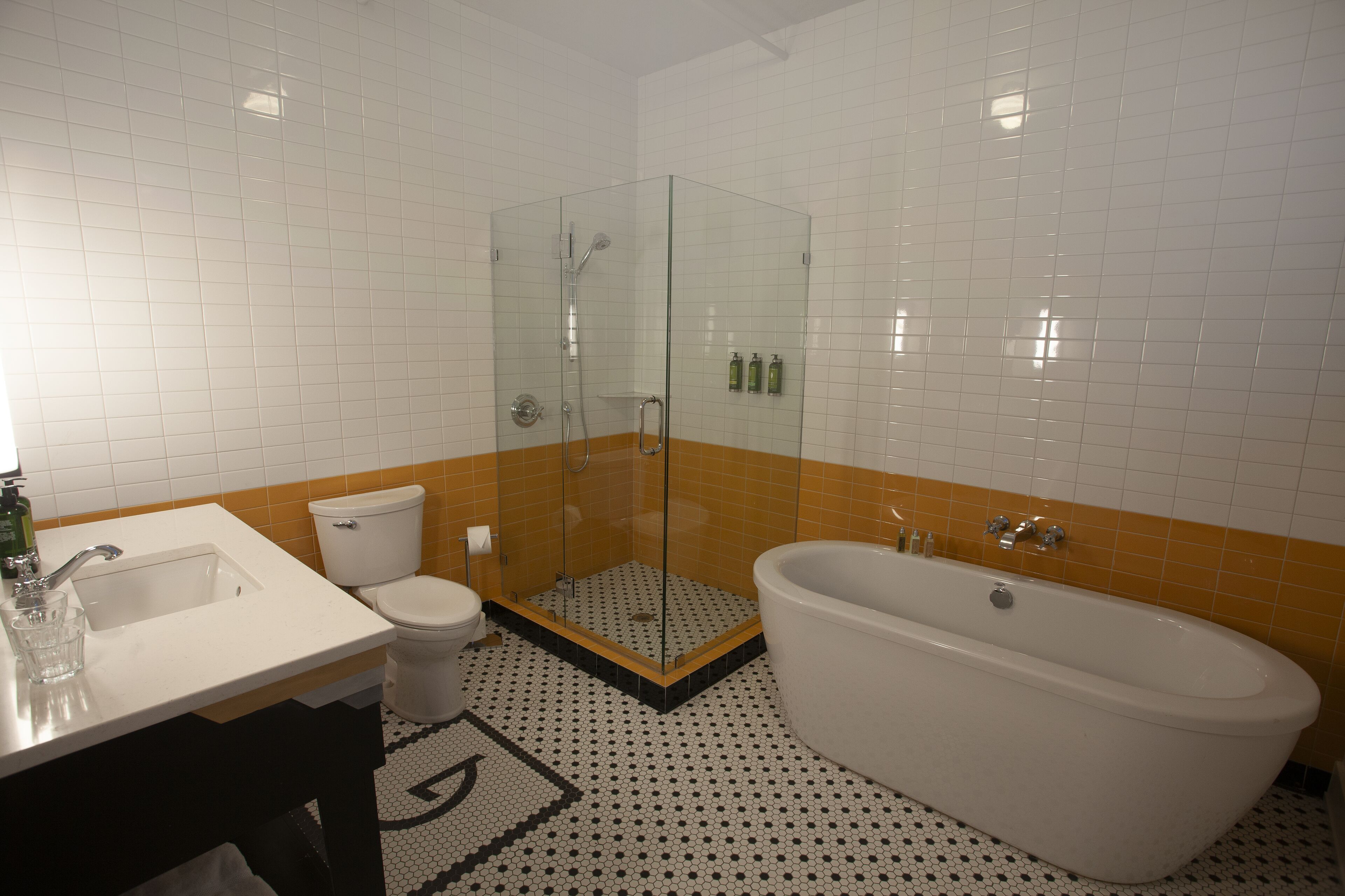 Une salle de bain avec une douche à parois de verre, un lavabo blanc, des toilettes et une baignoire sur pieds.