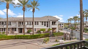A multi-story residential building with a symmetrical facade, multiple balconies, and a landscaped driveway with palm trees. - SWSS 3BR Kierland Greens Condo | Pool, Hot Tub, Golf Access & Gated Community (Scottsdale)