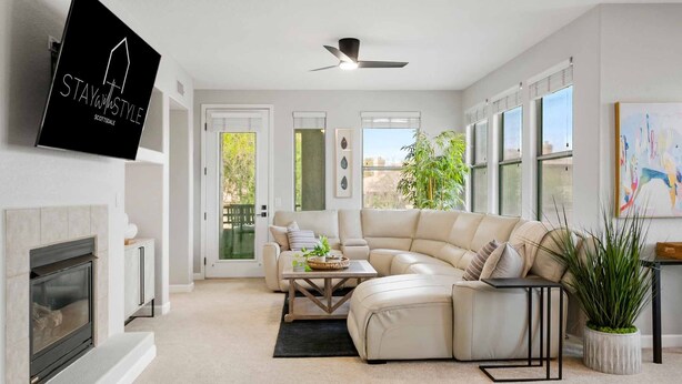 A modern living room with a fireplace, a sectional sofa, a coffee table, and a television mounted on the wall. - SWSS 3BR Kierland Greens Condo | Pool, Hot Tub, Golf Access & Gated Community (Scottsdale)