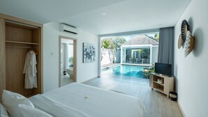 A modern hotel room with a large bed, a walk-in closet, a TV, and a view of a swimming pool.