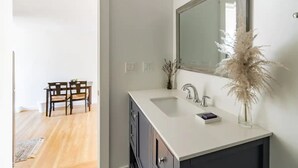 Une salle de bain moderne avec un grand miroir, des meubles sombres et un plan de toilette blanc.