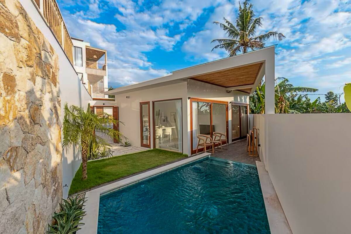 Ein modernes Haus mit Swimmingpool, einer Steinmauer und einem Garten.