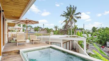 Ein Poolbereich mit Holzterrasse, Liegestühlen und Sonnenschirmen.