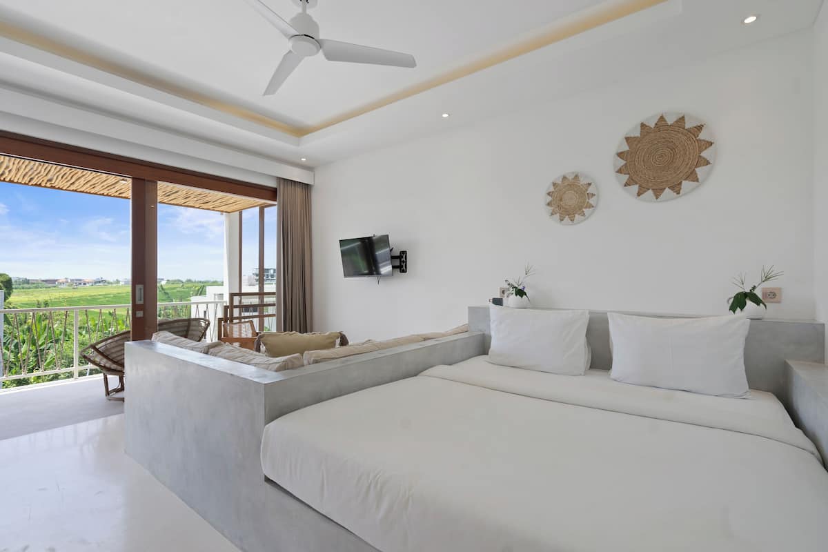 Ein modernes Schlafzimmer mit einem großen Bett, einem Fernseher und einem Balkon mit Blick auf die Landschaft.