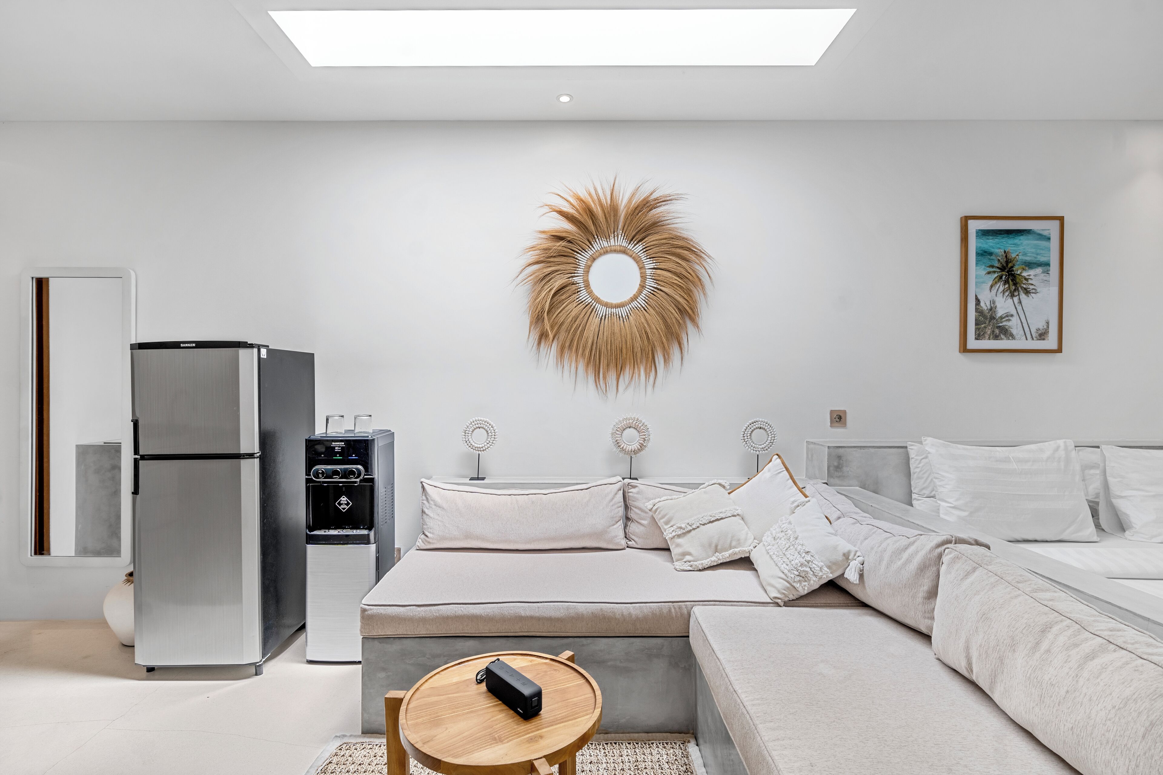 A modern bedroom with a bed, bedside tables, a refrigerator, and a water dispenser.