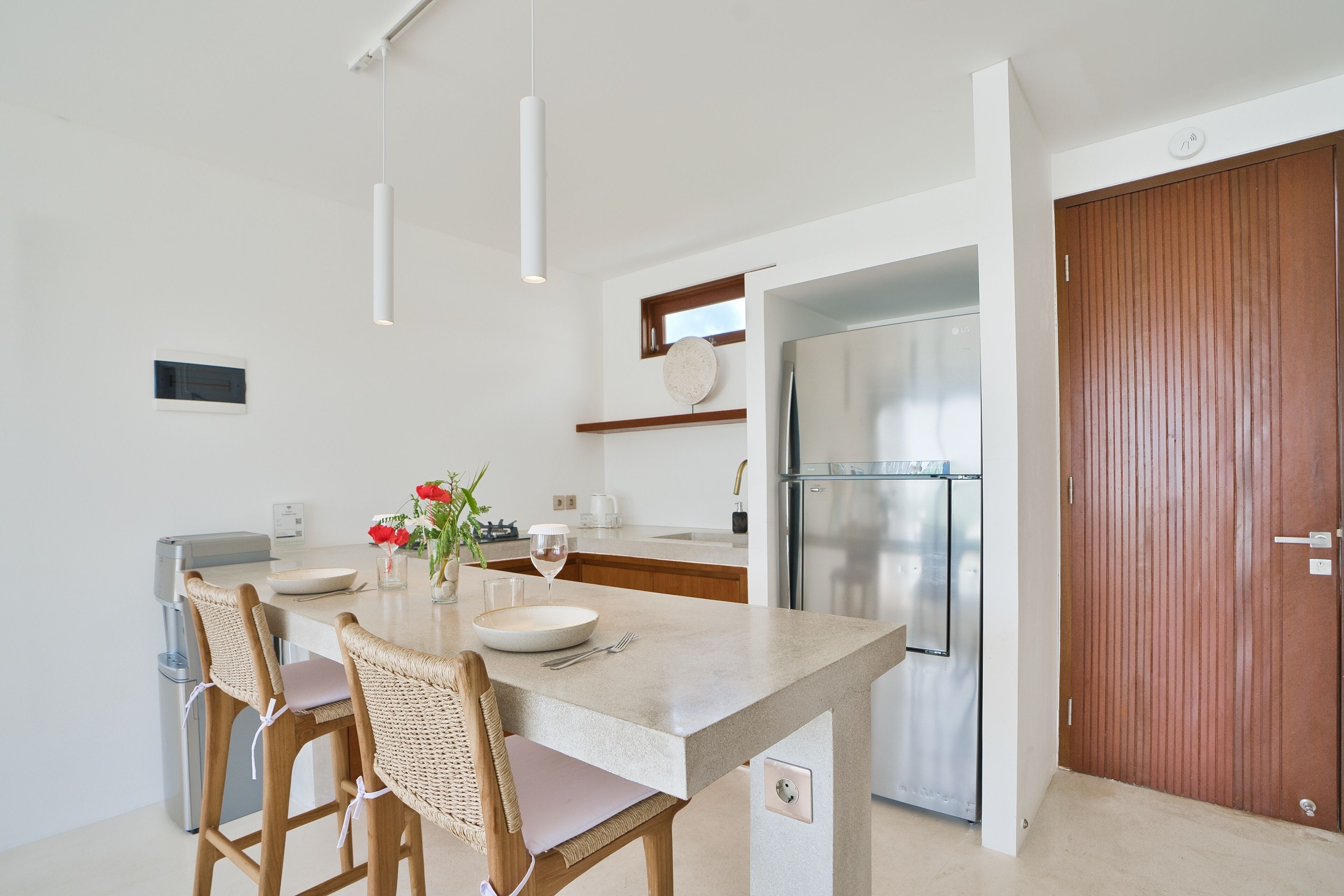 A modern kitchen with a central island, stainless steel appliances, and a wooden door.