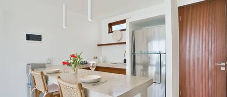 A modern kitchen with a central island, stainless steel appliances, and a wooden door.