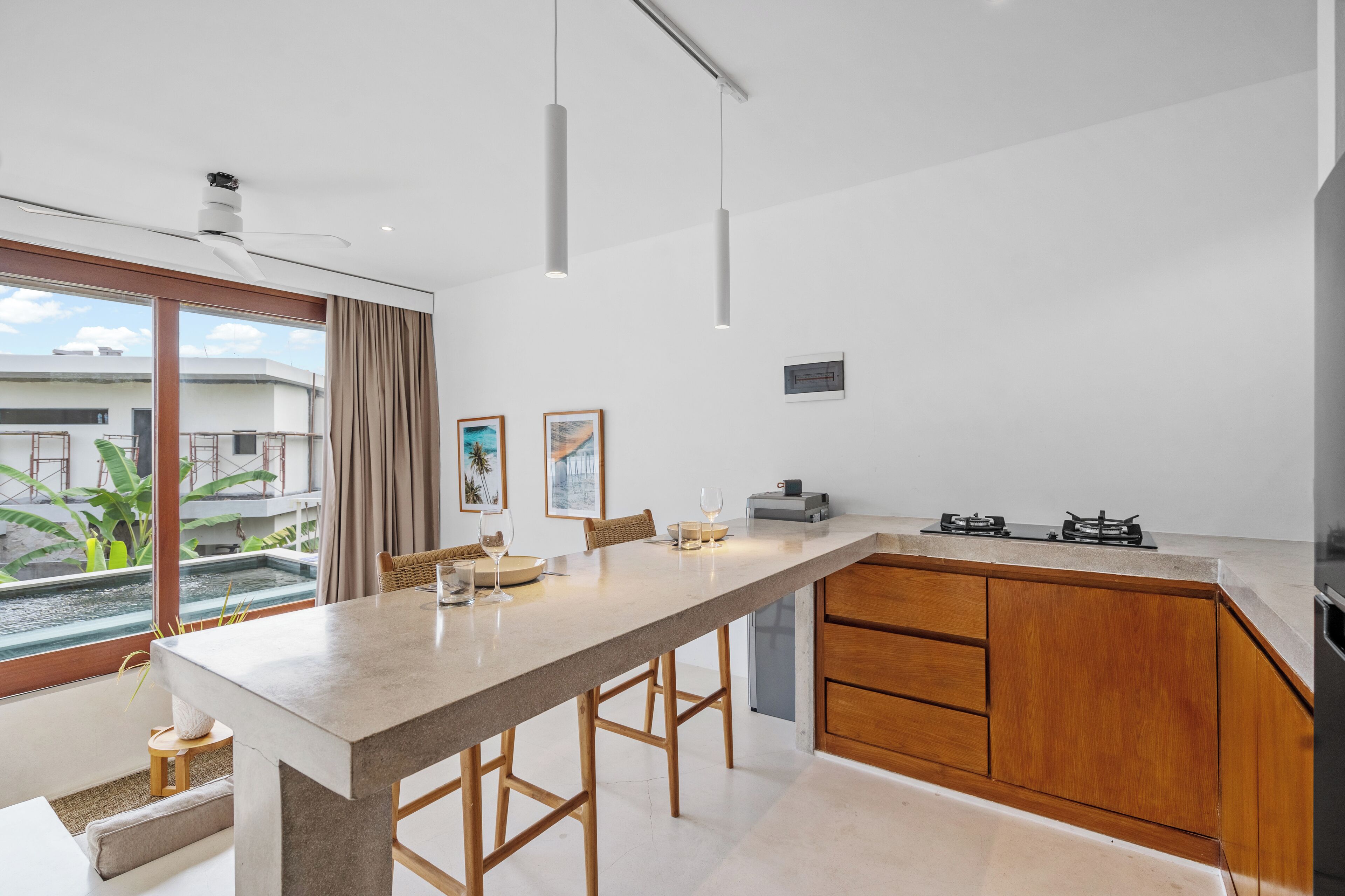 A modern kitchen with a large island, wooden cabinets, and a view of the outside.
