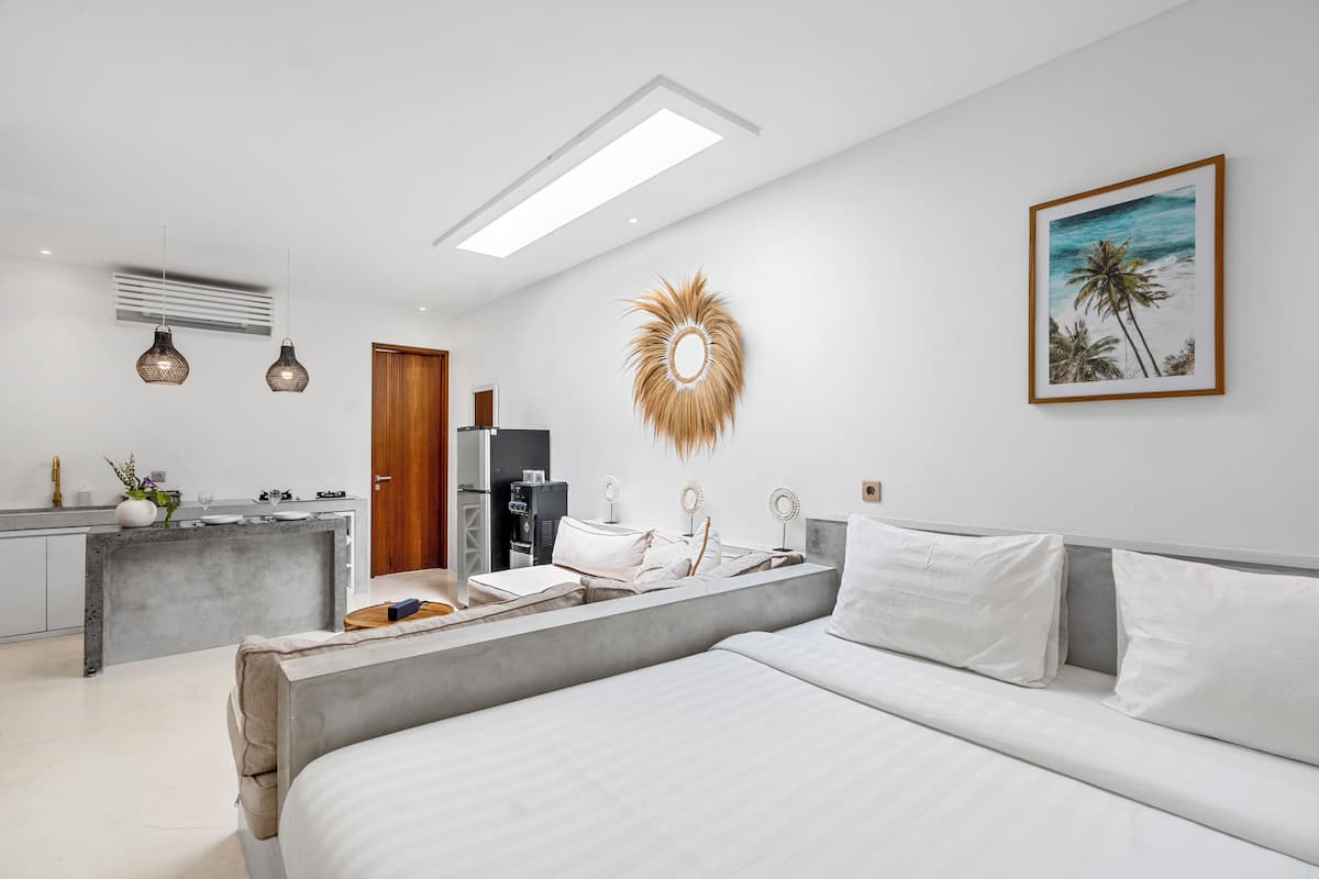 Ein modernes Schlafzimmer mit einem großen Bett, einem Schreibtisch und einer Küchenzeile.