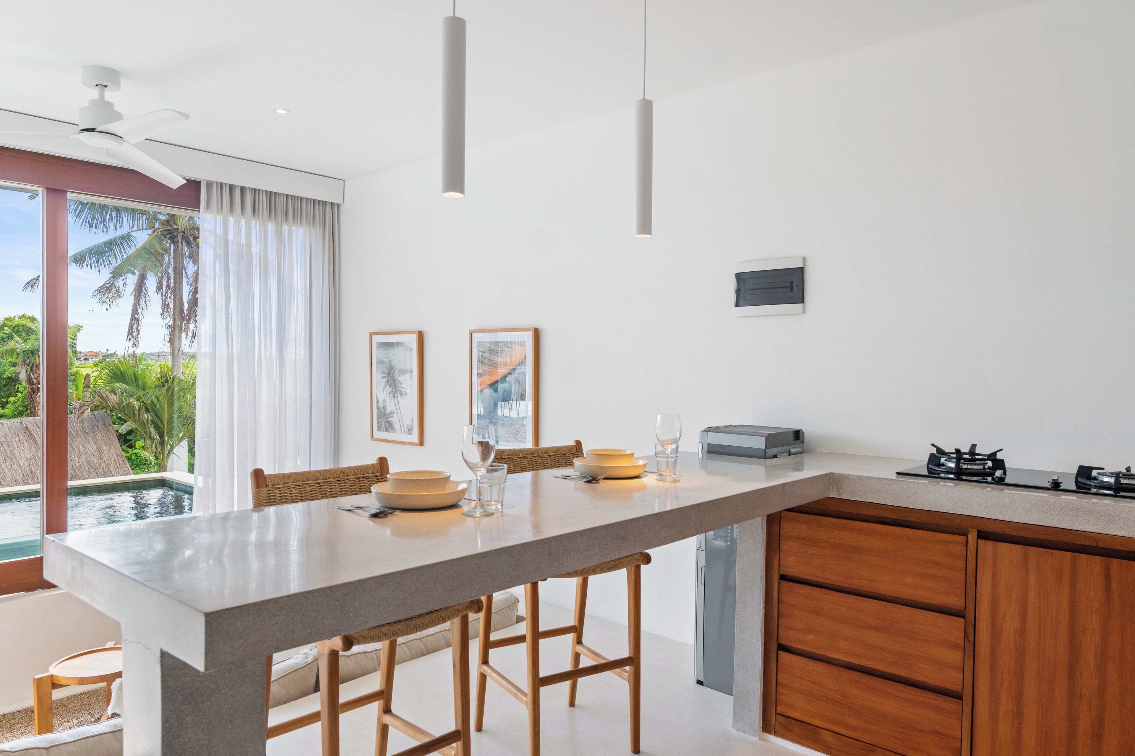 Een moderne keuken met een groot eiland, houten kastjes en uitzicht op een zwembad.
