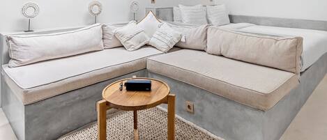 Een moderne woonkamer met een hoekbank, een ronde houten salontafel en een decoratieve spiegel aan de muur.