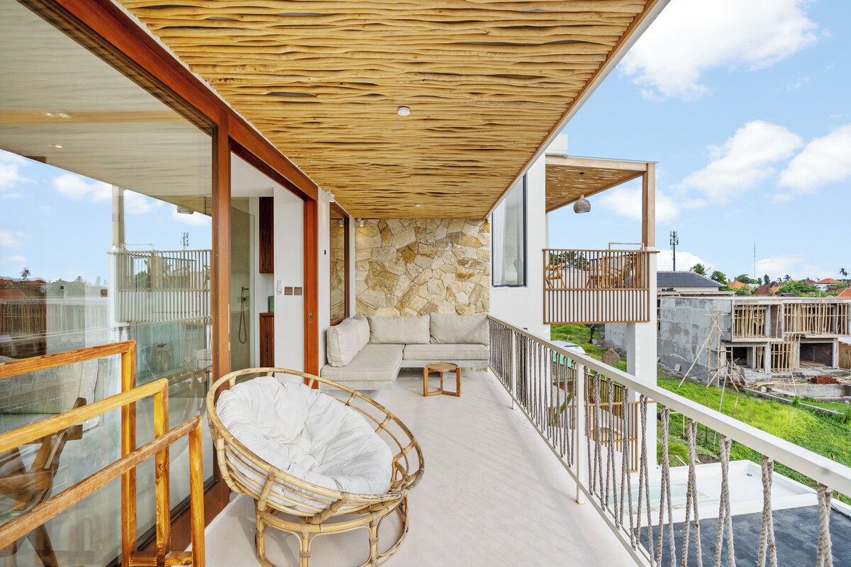 A balcony with a stone wall, a wicker chair, and a sofa.