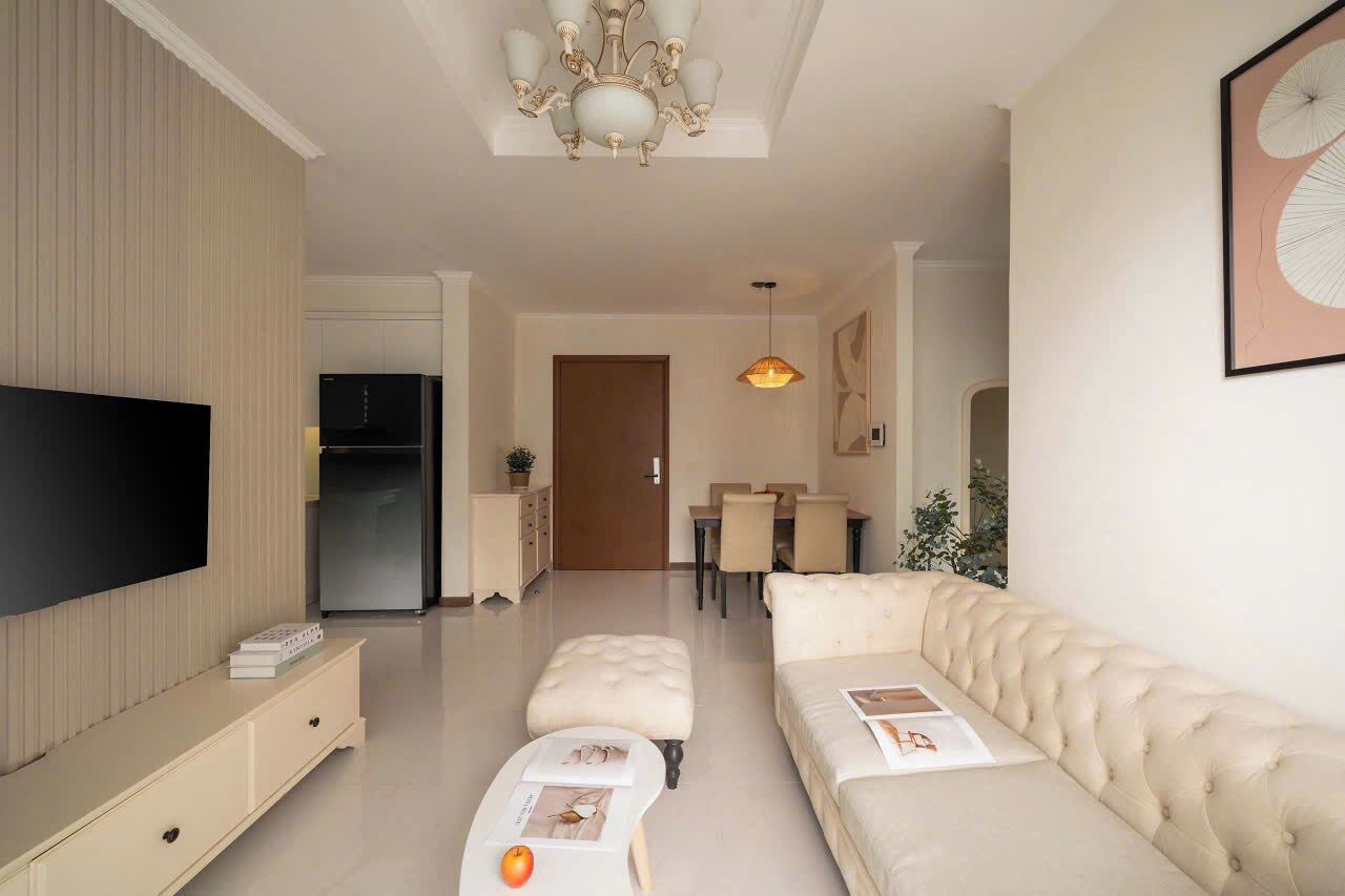 A modern living room with a flat-screen TV, a sofa, a coffee table, and a dining area with a table and chairs.