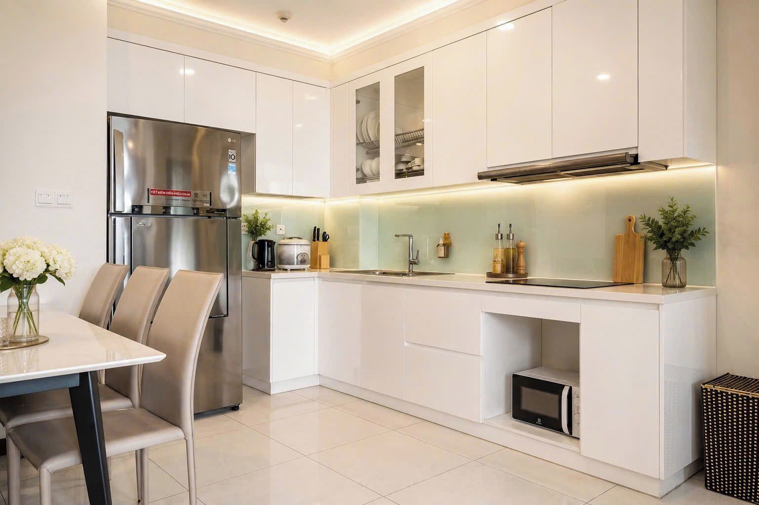 Cocina moderna con armarios blancos, electrodomésticos de acero inoxidable y un comedor con mesa y sillas.