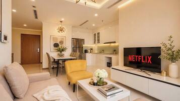 Un salón moderno con sofá, sillón amarillo, mesa de centro y un televisor mostrando el logotipo de Netflix.