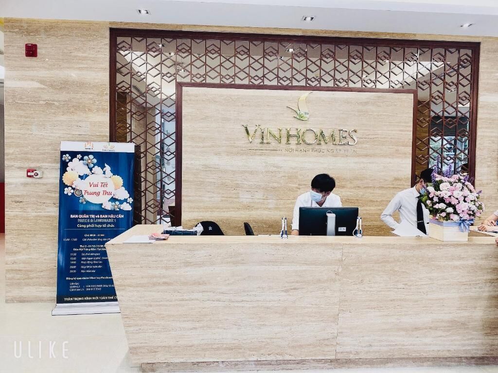 Una reception moderna presso Vinhomes, con un computer e un'elegante composizione floreale.