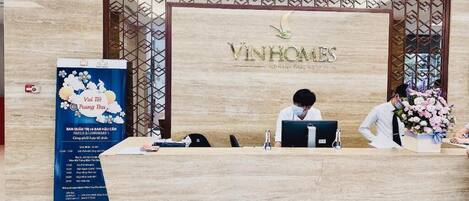 Una reception moderna presso Vinhomes, con un computer e un'elegante composizione floreale.