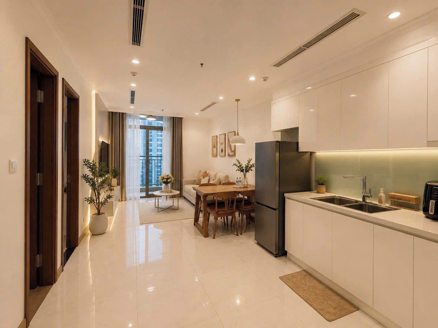 Una cocina moderna con refrigerador empotrado, un comedor con mesa y sillas, y vista a un balcón.