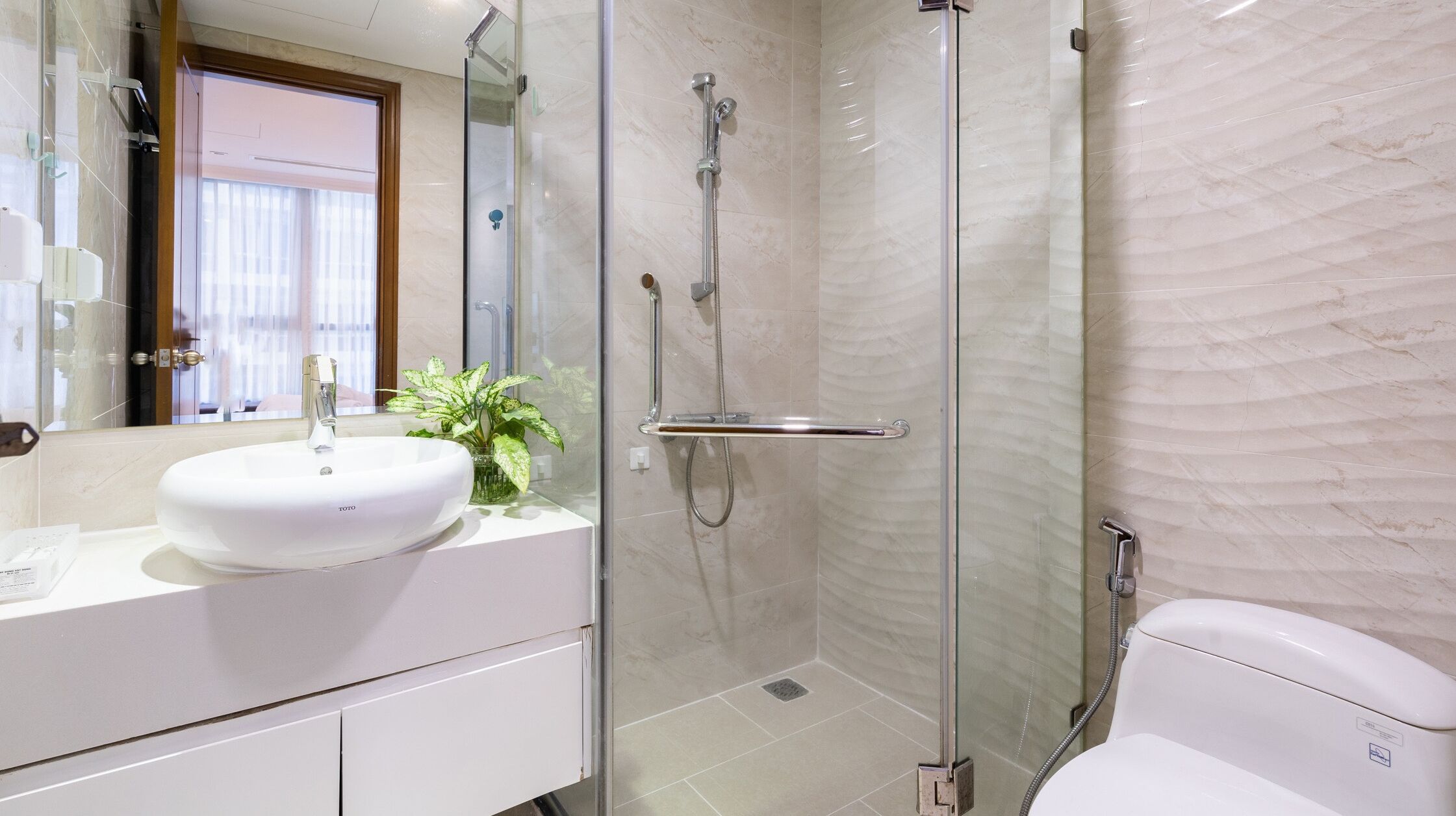 Une salle de bain moderne avec un lavabo blanc, une douche en verre et des toilettes.