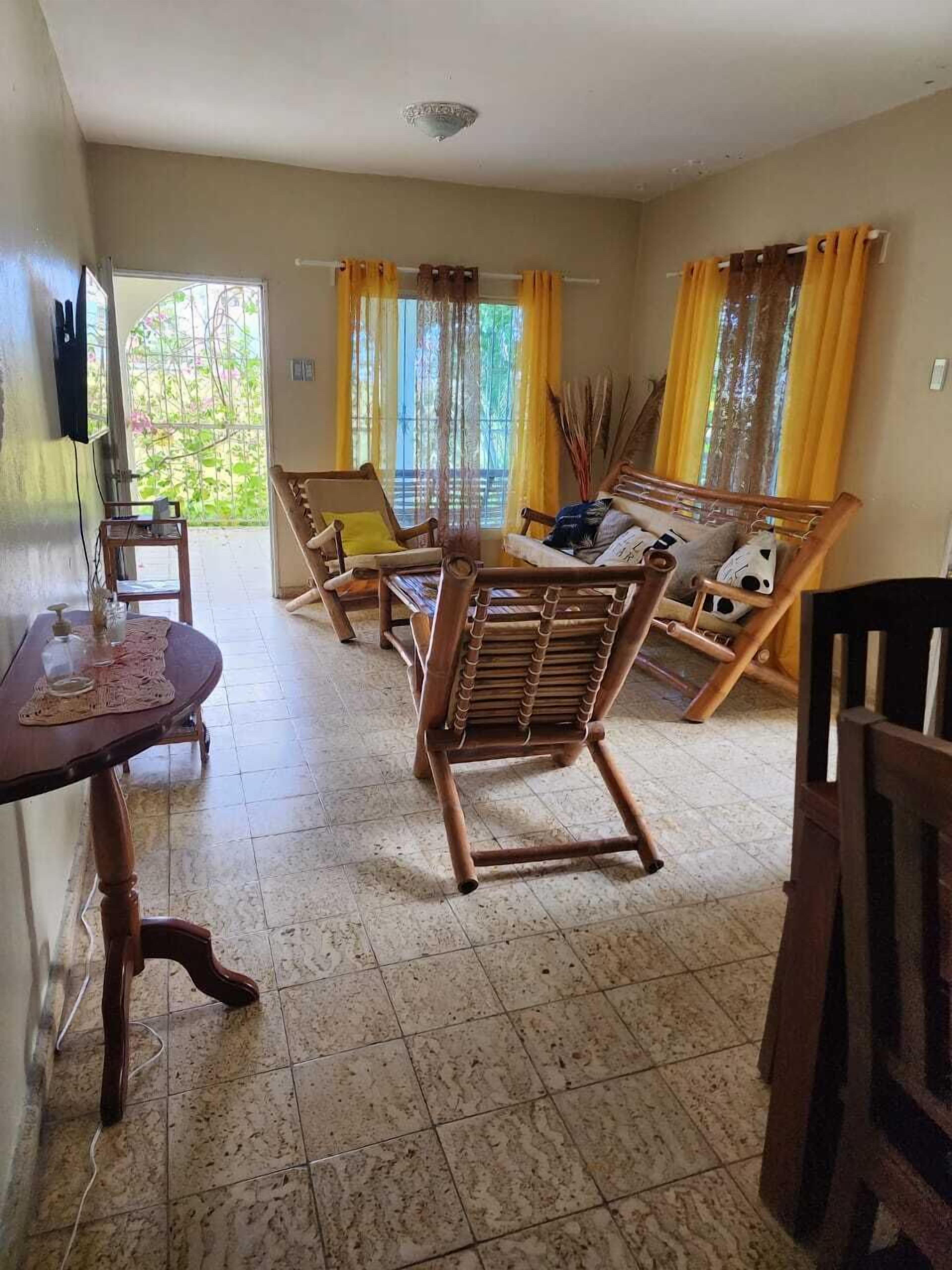 Amplia sala de estar con un sofá de madera, dos mecedoras y una mesa de comedor.