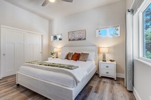 A bedroom with a large bed, two bedside tables, a ceiling fan, and a window with curtains. - Mountain Oasis (Florissant)