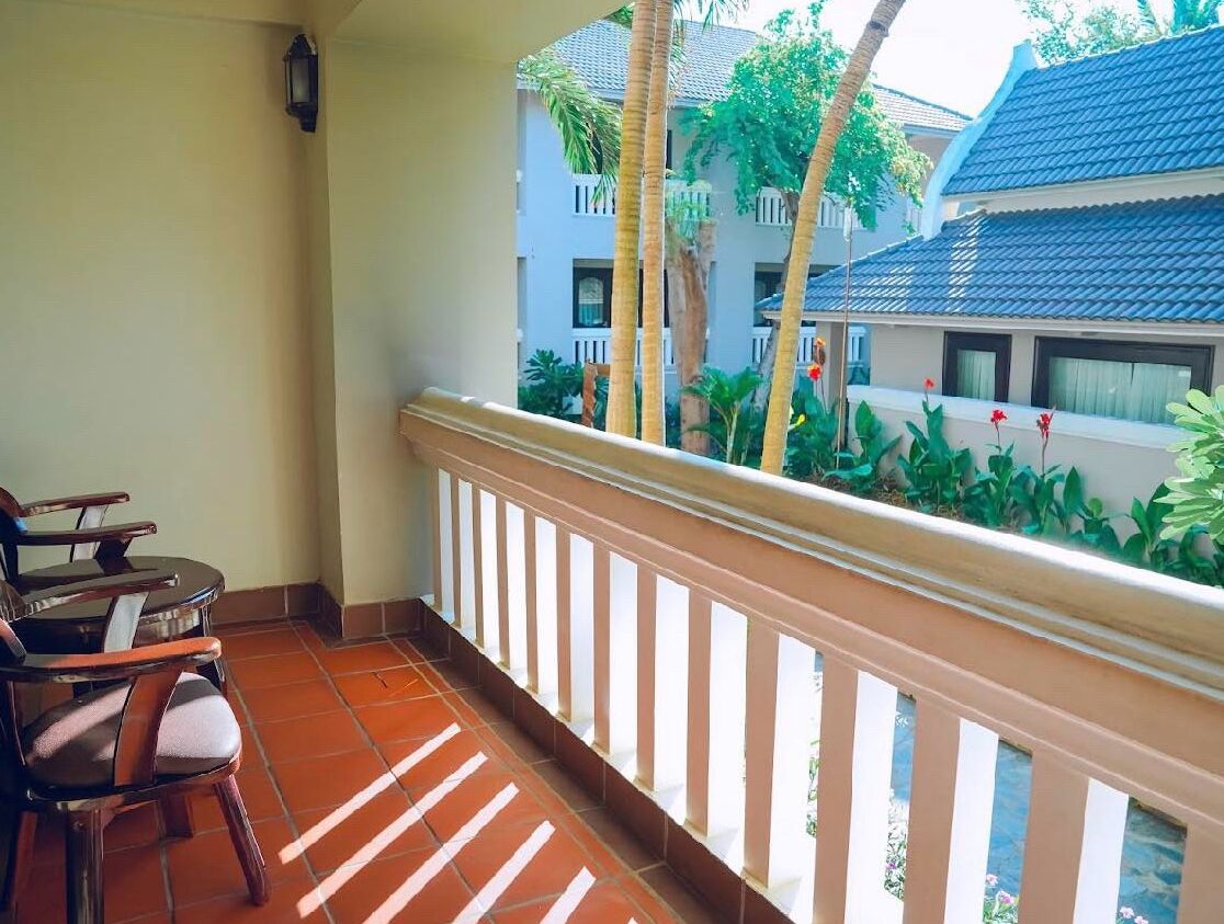 A balcony with a view of a building and palm trees.
