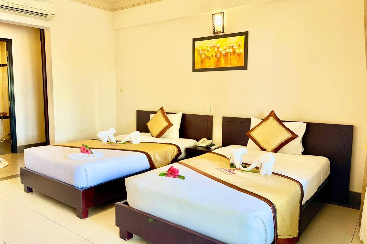 Habitación de hotel con dos camas, un cuadro en la pared y un teléfono en la mesita de noche.