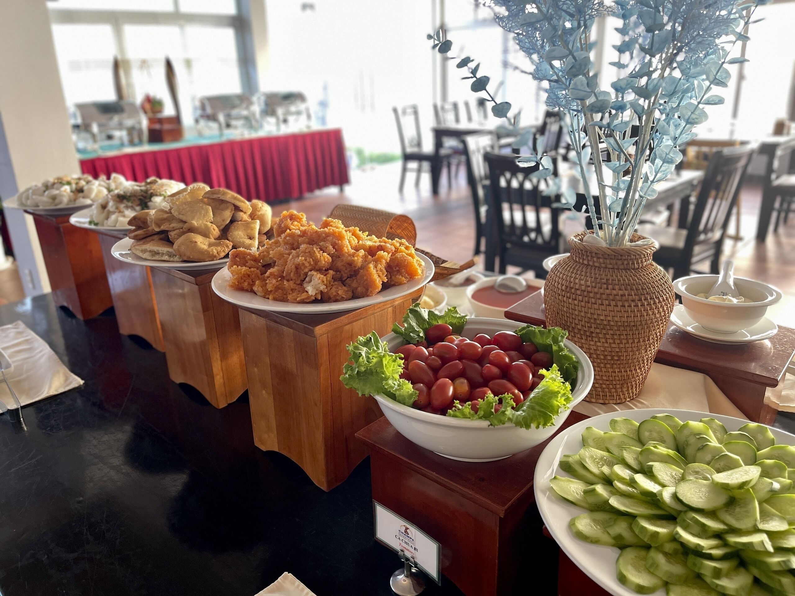 A buffet table with various dishes including fried rice, bread, grapes, and cucumber slices.